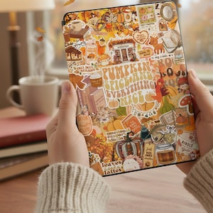 May include: A Kindle e-reader with a fall-themed sticker design. The stickers feature pumpkins, books, coffee, and the text "Pumpkin Spice and Everything Nice." The e-reader is held in front of a blurred background with falling leaves.