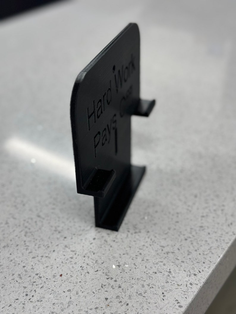 May include: Black plastic sign with the text "Hard Work Pays Off" in white lettering.