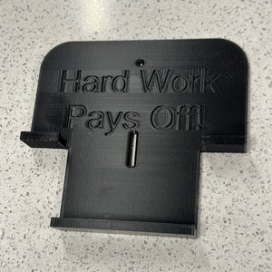May include: Black plastic sign with the text "Hard Work Pays Off!" printed on it.