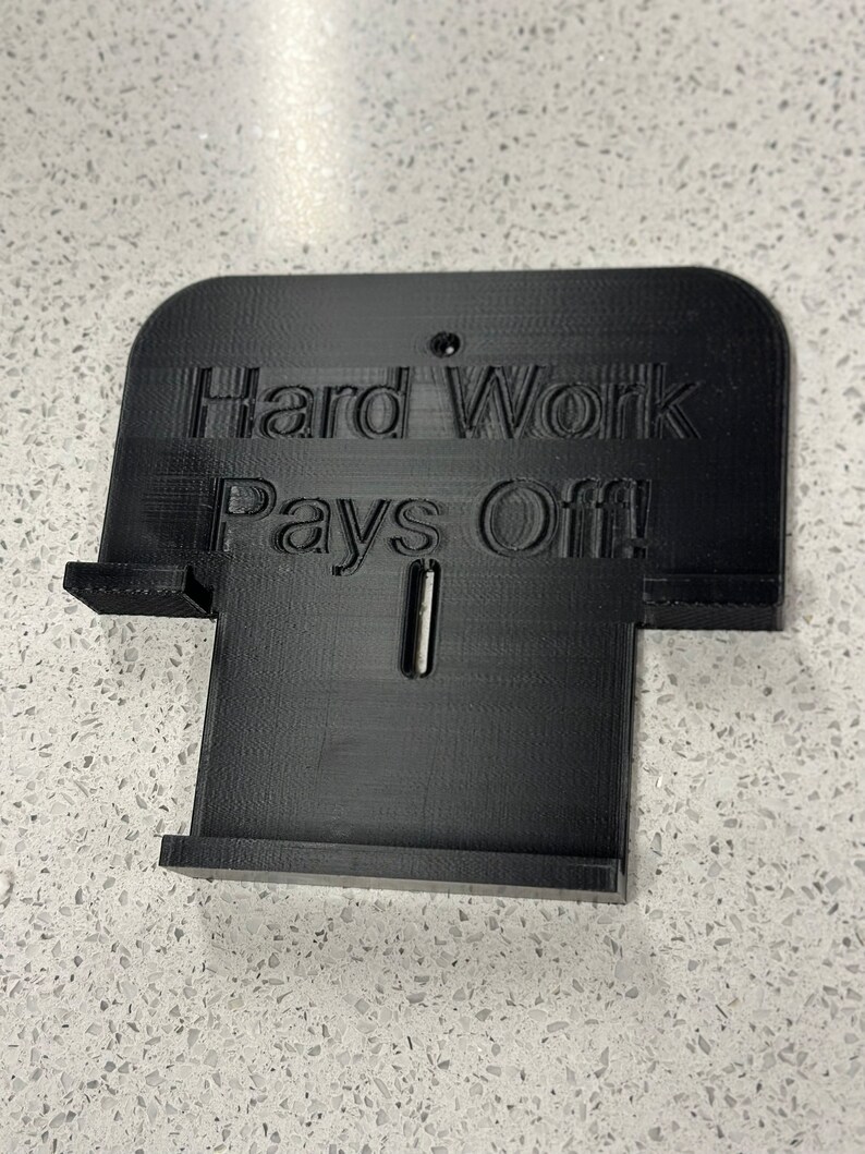 May include: Black plastic sign with the text "Hard Work Pays Off!" printed on it.