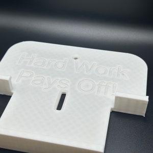 May include: White plastic phone stand with the words "Hard Work Pays Off!" printed on the front.