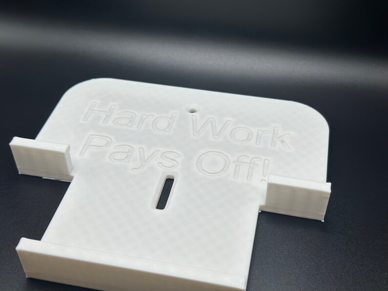 May include: White plastic phone stand with the words "Hard Work Pays Off!" printed on the front.