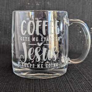 May include: A clear glass coffee mug with a white inscription that reads "Coffee gets me started Jesus keeps me going".