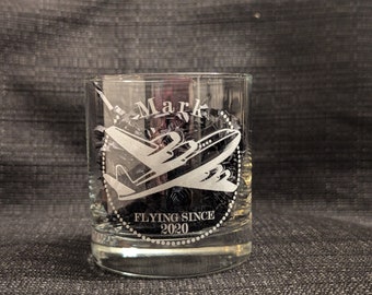 May include: A clear glass tumbler with an etched design of an airplane and the text "Mark Flying Since 2020".