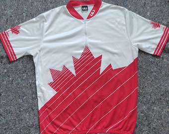 May include: White cycling jersey with a red Canadian flag design. The jersey has a zipper and the text "LG1" on the collar.