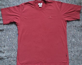 May include: A burgundy short-sleeved t-shirt with a small embroidered Adidas logo on the front.