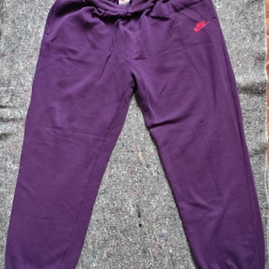 Op de afbeelding: Paarse sweatpants met een wit trekkoord en een rood Nike-logo op het rechterbeen.