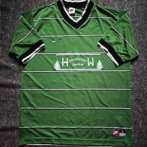 May include: Green and white striped jersey with a V-neck collar and short sleeves. The jersey features the text "Privatwald Service" and a Nike logo. The sleeves have black and white trim. The jersey is a size large.