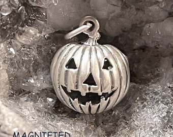 Op de afbeelding: Een zilveren bedel in de vorm van een jack-o'-lantern. De bedel heeft een gedetailleerd gesneden gezicht en hangt aan een lus.