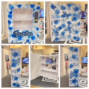 May include: A white vending machine with a blue rose pattern. The machine has a keypad, a display, and the name "Jasmine" in cursive. The interior has shelves. The floral design covers the entire exterior.