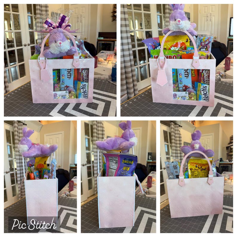 May include: A pink Easter gift basket with a plush purple bunny and assorted candies. The basket has a clear window showing the treats inside. The handle is pink and the basket is filled with snacks.