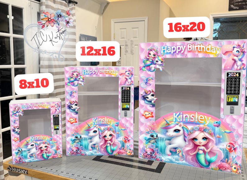May include: Three pink and white birthday-themed display boxes in 8x10, 12x16, and 16x20 inch sizes. Each box features a mermaid, unicorn, and rainbow design with the text "Happy Birthday" and "Kinsley".