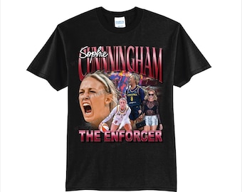 Op de afbeelding: Zwart t-shirt met een afbeelding van Sophie Cunningham, de tekst "Sophie Cunningham" en "The Enforcer". De afbeelding bevat afbeeldingen van Cunningham in actie, met een basketbal en andere spelers.