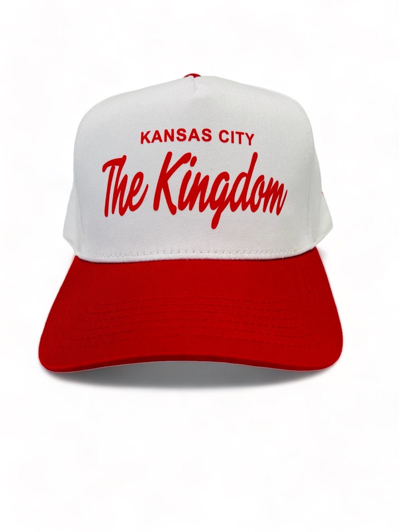 May include: White and red baseball cap with the text "KANSAS CITY The Kingdom" in red lettering.