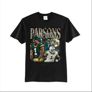 May include: Black t-shirt featuring a graphic of a football player in a green and gold uniform. The shirt has the name "Parsons" in gold lettering. The image includes action shots of the player.