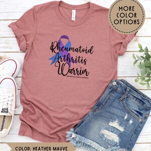 May include: Heather mauve t-shirt with a purple ribbon and the text "Rheumatoid Arthritis Warrior #rheumatoidarthritisawareness".