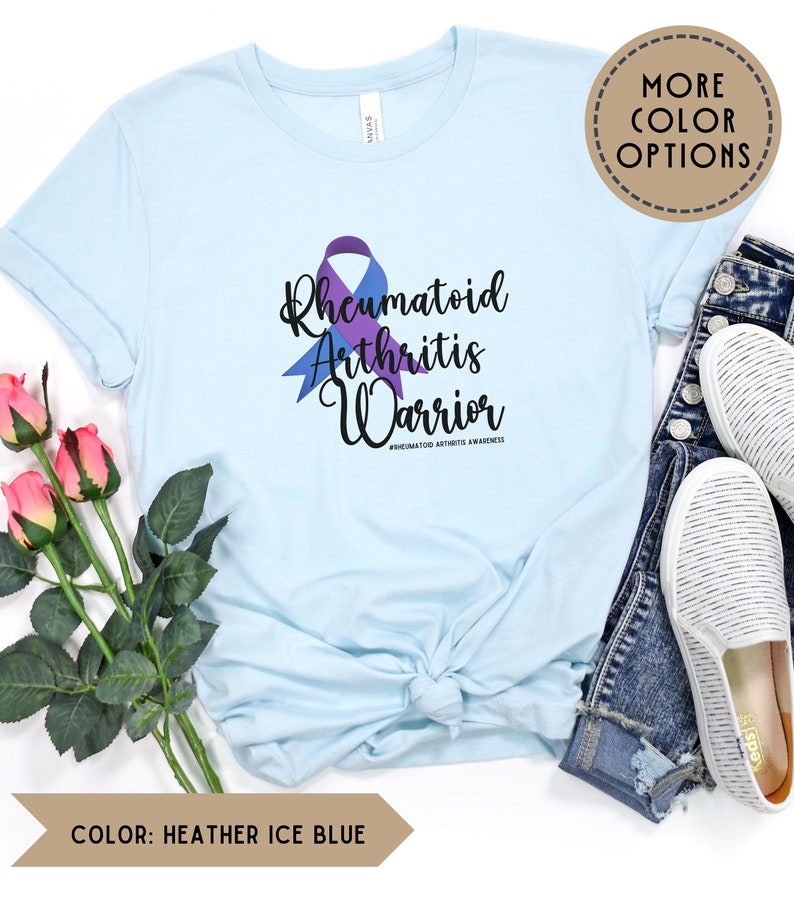 May include: A light blue t-shirt with a purple and blue ribbon and the text "Rheumatoid Arthritis Warrior #RHEUMATOID ARTHRITIS AWARENESS".