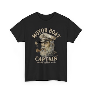 May include: Black t-shirt featuring a vintage illustration of a motorboat captain. The design includes the text "MOTOR BOAT CAPTAIN" above an image of a bearded man in a captain's hat smoking a pipe. The text "MOTOR BOATIN' S.O.B." is below.