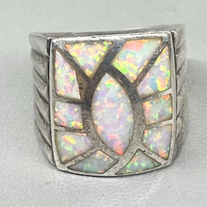 May include: A silver ring with a white opal stone set in a geometric design.