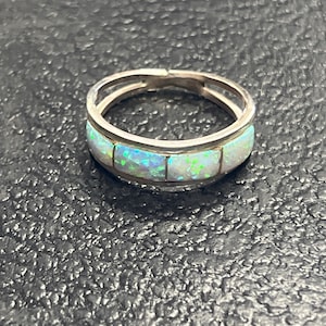 May include: A silver ring with a band of white opal stones.