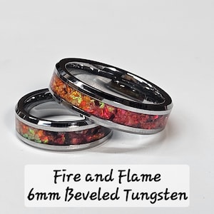 Può includere: Due anelli in tungsteno bisellati da 6 mm con un designo a fuoco e fiamma. Gli anelli hanno una fascia argentata con intarsi di opale rosso e arancione.