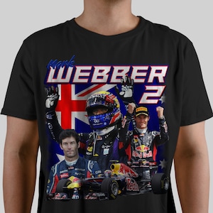 May include: Black t-shirt with a graphic of Formula One driver Mark Webber, wearing a racing suit and helmet, holding up his hands in victory. The graphic also includes an Australian flag and the number "2".