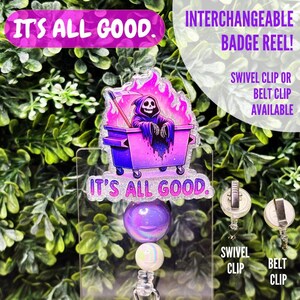 Könnte beinhalten: Ein durchsichtiger Plastik-Badgehalter mit einem glitzernden Design in Lila und Pink, das einen Cartoon-Sensenmann zeigt, der in einem brennenden Müllcontainer sitzt. Der Text "It's All Good" ist auf dem Design gedruckt. Der Badgehalter hat eine lila und schillernde Perle und eine weiße Perle. Der Badgehalter hat einen Drehclip und einen Gürtelclip.
