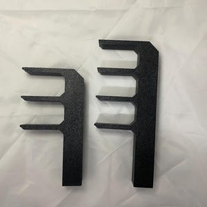 May include: Two black plastic shelf brackets with three shelves each. The brackets are designed to be mounted to a wall.