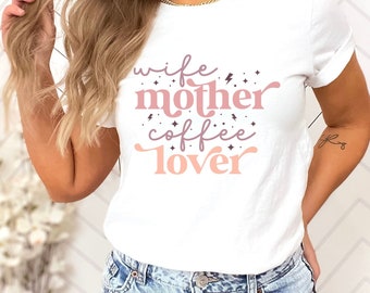 May include: White t-shirt with the text "wife mother coffee lover" in pink and purple lettering with small stars and lightning bolts.