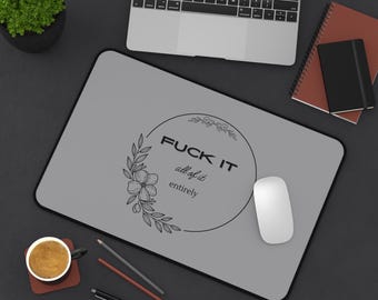 Könnte beinhalten: Ein graues Mauspad mit schwarzem Rand zeigt den Text "FUCK IT all of it entirely" in einem floralen Kranz. Eine weiße Computermaus befindet sich rechts. Ein Laptop, ein Notizbuch und eine Kaffeetasse sind ebenfalls sichtbar.