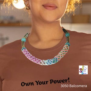Könnte beinhalten: Eine farbenfrohe Halskette mit geflochtenem Design, die rosa, blaue, grüne und orangefarbene Stränge aufweist. Die Halskette hat dekorative Metallelemente und wird um den Hals getragen. Das Bild enthält auch den Text "Own Your Power!" und "3050 Balcomera".