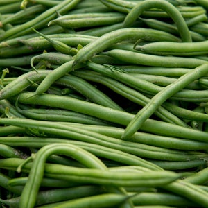 May include: A close-up of a pile of fresh green beans. The beans are a vibrant green, long, and slender, with a slightly curved shape. The image highlights the natural texture and colour of the beans, suggesting freshness and a healthy food source.