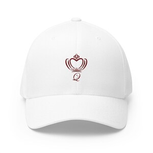May include: White baseball cap with a curved brim. The cap features a burgundy crown design with the letter "Q" underneath. The crown is heart-shaped with a fleur-de-lis on top. A casual accessory.
