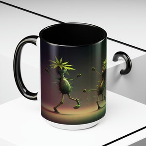 May include: A white ceramic mug with a black handle and a black rim. The mug features a colorful illustration of two cartoon characters with green hair and bodies dancing on a dark background.