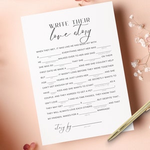 以下が含まれることがあります： 「彼らのラブストーリーを書く」というテキストと、パーソナライズされたラブストーリーを作成するための空白を埋めるためのプロンプトが書かれた、印刷可能なゲームカード。カードは白地に黒文字です。