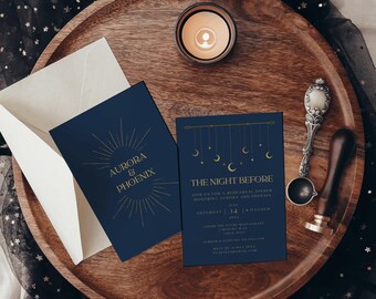May include: A dark blue invitation set with gold foil text reading Aurora & Phoenix and The Night Before. The design features celestial motifs including stars, moons, and sunburst rays. Includes a white envelope, a metal wax seal spoon, and a wooden handle wax seal stamp.