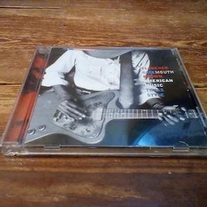 May include: CD case featuring Clarence Gatemouth Brown's album. The cover art shows a black and white image of a person playing a guitar. The album title and other text are visible on the cover. The CD case is clear.