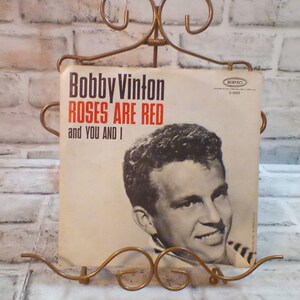 Puede incluir: Un disco de vinilo vintage de Bobby Vinton titulado "Roses Are Red and You And I" en el sello Epic. La portada del disco presenta una foto en blanco y negro de Bobby Vinton.