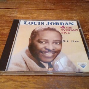 May include: CD case featuring Louis Jordan & His Tympany Five. The album cover has a sepia-toned portrait of Louis Jordan. The album title is "G.I. Jive". The CD case is on a wooden surface.
