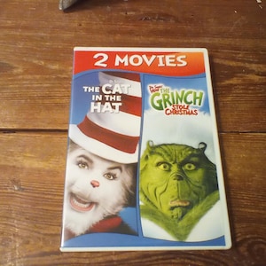 May include: A DVD case featuring 2 Movies with Dr. Seuss's The Cat in the Hat and How the Grinch Stole Christmas. The cover displays the Cat in the Hat wearing a red and white striped hat on the left and the green Grinch character on the right.