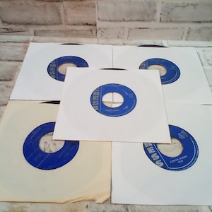 May include: Six white paper record sleeves with blue labels. The labels have the word "Chess" printed in silver lettering. One label has the text "Chuck Berry 1747".