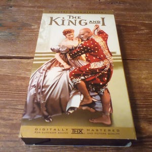 May include: A VHS tape of Rodgers & Hammerstein's The King and I. The cover features a man and a woman dancing, with the man in a red and gold outfit and the woman in a large, light-colored gown. The text reads The King and I and THX.