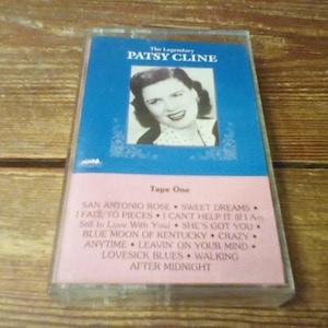 May include: A cassette tape titled The Legendary Patsy Cline featuring a black and white portrait of the artist on a blue background. The lower pink section lists Tape One and song titles including San Antonio Rose, Sweet Dreams, and Crazy.