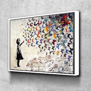 May include: A framed canvas art print featuring a silhouette of a child reaching towards a swarm of colorful butterflies. The butterflies are in shades of red, orange, blue, and yellow, set against a textured brick and wall background.