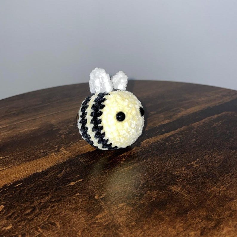 Peut inclure: Un jouet d'abeille au crochet fait &agrave; la main, avec une texture douce et moelleuse. L'abeille a un corps jaune avec des rayures noires, de petites ailes blanches et des yeux en perles noires. Un objet d&eacute;coratif charmant.