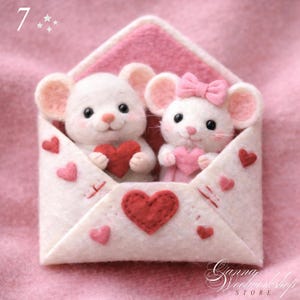 Puede incluir: Artesanía de fieltro que presenta dos ratones blancos sosteniendo corazones dentro de un sobre rosa y blanco. Los ratones tienen orejas rosas y ojos negros. El sobre está decorado con corazones rojos. La imagen tiene un ambiente suave y romántico.