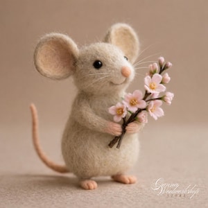 Könnte beinhalten: Eine handgefertigte Filzmaus-Figur in Beige, die einen kleinen Strauß rosa Blumen hält. Die Maus hat große, abgerundete Ohren, eine rosa Nase und einen langen, gebogenen Schwanz. Die Figur ist detailliert und hat einen lächelnden Ausdruck.
