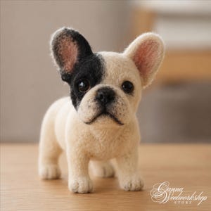 May include: A needle-felted French Bulldog figurine with cream-colored fur and a black patch over its left eye and ear. The sculpture features dark, glossy eyes, a black nose, and upright ears. The text Ganna Woolworkshop Store is visible.