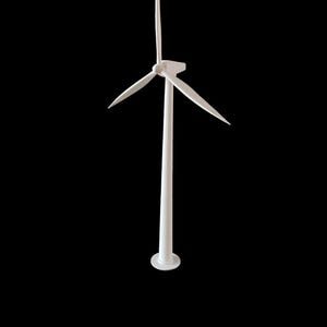 Puede incluir: Modelo blanco de aerogenerador con tres aspas y una estructura de soporte delgada. El modelo se alza sobre una base circular sobre un fondo negro, resaltando su diseño minimalista. La altura es de unos 20 cm.