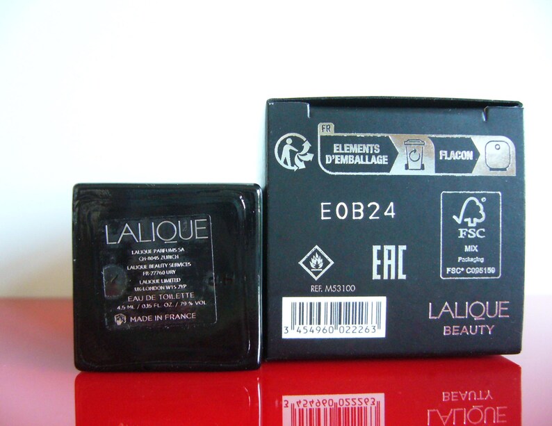 Peut inclure: Un ensemble de flacon et de bo&icirc;te noirs Lalique Eau de Toilette. Le flacon est carr&eacute; avec une &eacute;tiquette indiquant "EAU DE TOILETTE 4,5 ml / 0,15 FL. OZ. / 79 % VOL". La bo&icirc;te porte la mention "LALIQUE BEAUTY".
